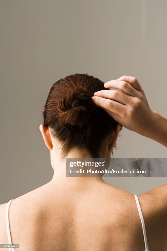 Woman styling hair, rear view