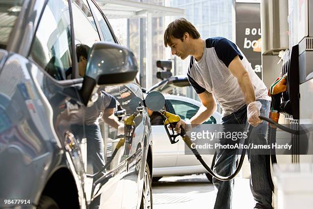 man refueling vehicle at gas station - filling petrol stock pictures, royalty-free photos & images