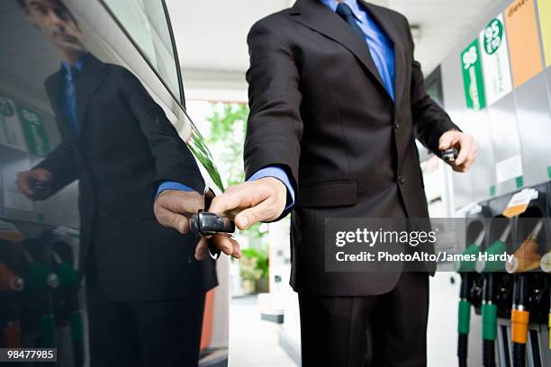 well-dressed man getting into car after refueling at gas station - station service france stock pictures, royalty-free photos & images