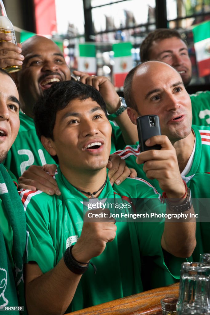 Men in sports bar using camera phone