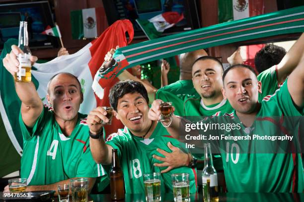 cheering men drinking in sports bar - beer bottle mouth stock-fotos und bilder