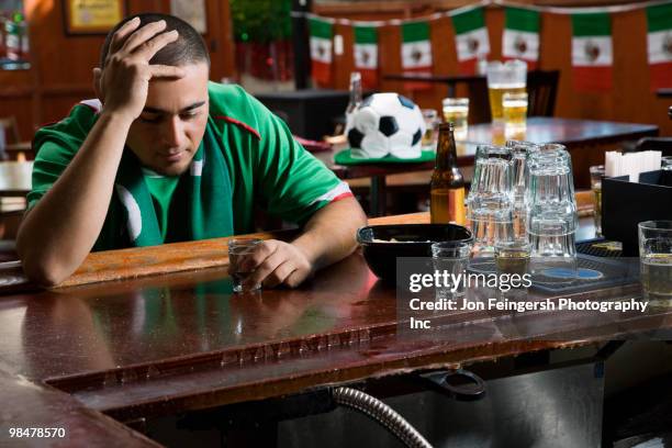 unhappy man drinking in sports bar - spirit 32 ストックフォトと画像