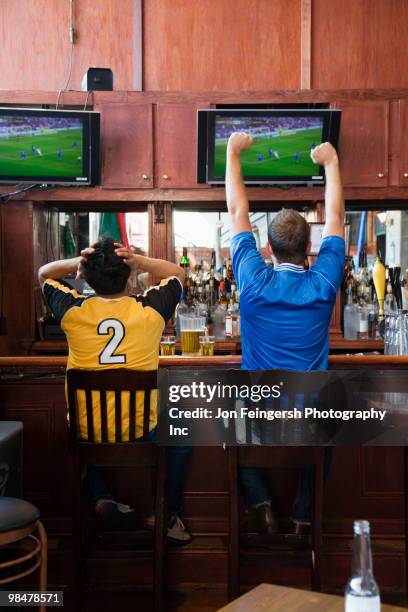 cheering men watching television in sports bar - american football strip fotografías e imágenes de stock