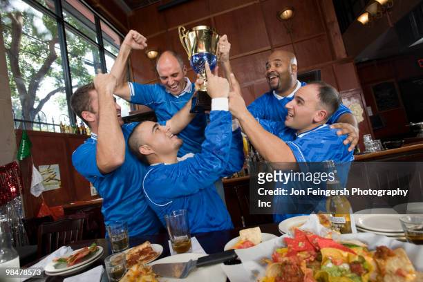 cheering teammates and man lifting trophy - jon feingersh stock pictures, royalty-free photos & images