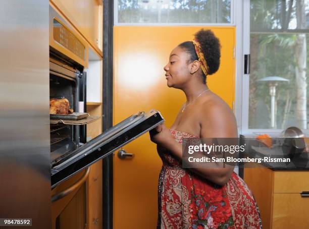 african american woman checking on food in oven - kitchen oven stock-fotos und bilder