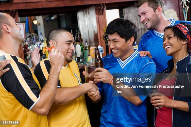 happy men shaking hands in sports bar - rivaliteit stockfoto's en -beelden