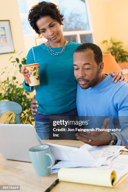 african american husband paying bills as wife watches - jon feingersh stock pictures, royalty-free photos & images