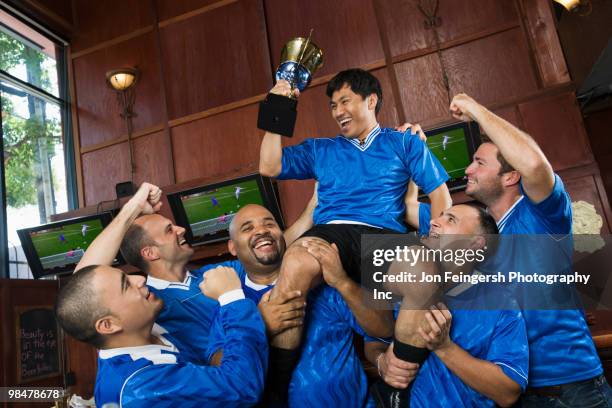 cheering teammates lifting man holding trophy - carrying tv stock pictures, royalty-free photos & images