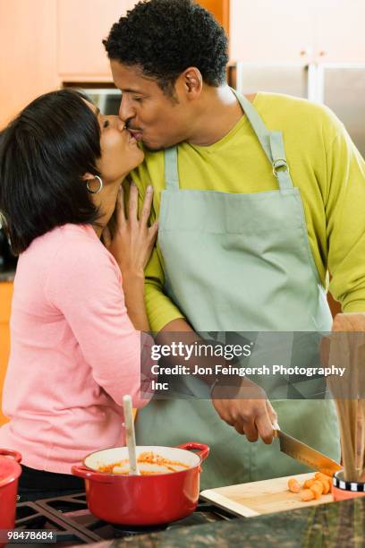 african american couple kissing in kitchen - jon feingersh stock pictures, royalty-free photos & images