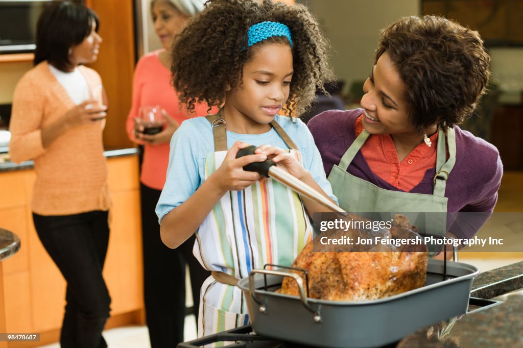 African American girl basting Thanksgiving turkey