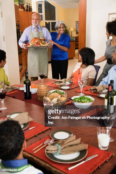 african american man serving thanksgiving turkey - jon feingersh stock pictures, royalty-free photos & images