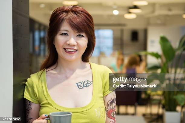 a woman entrepreneur who puts a tattoo to show a smile at a new office - hachioji fotografías e imágenes de stock