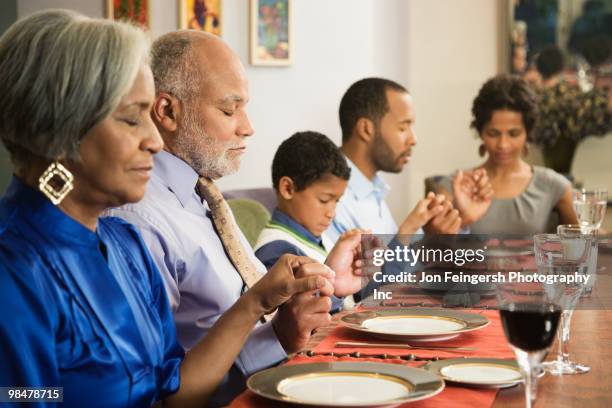 african american family saying grace at dining table - jon feingersh stock pictures, royalty-free photos & images