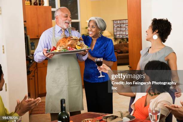 african american man serving thanksgiving turkey - jon feingersh stock pictures, royalty-free photos & images