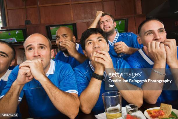 worried teammates watching television in sports bar - biting stock pictures, royalty-free photos & images