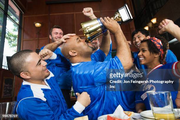 cheering teammates and man drinking from trophy - jon feingersh stock pictures, royalty-free photos & images