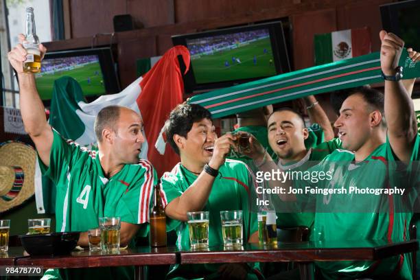 cheering men watching television in sports bar - beer bottle mouth stock pictures, royalty-free photos & images
