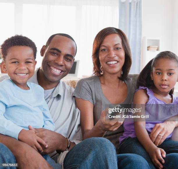 african american family watching television together - command sisters photos et images de collection