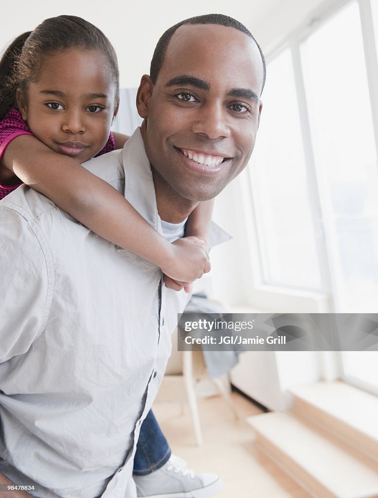 African American father carrying daughter on back