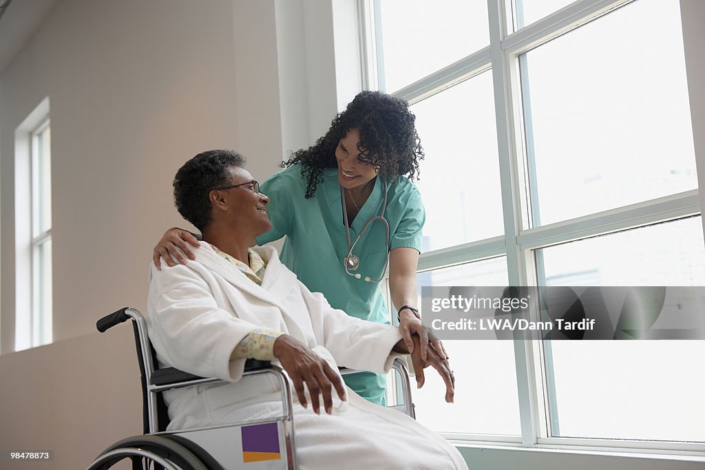 African American nurse checking on patient in wheel chair