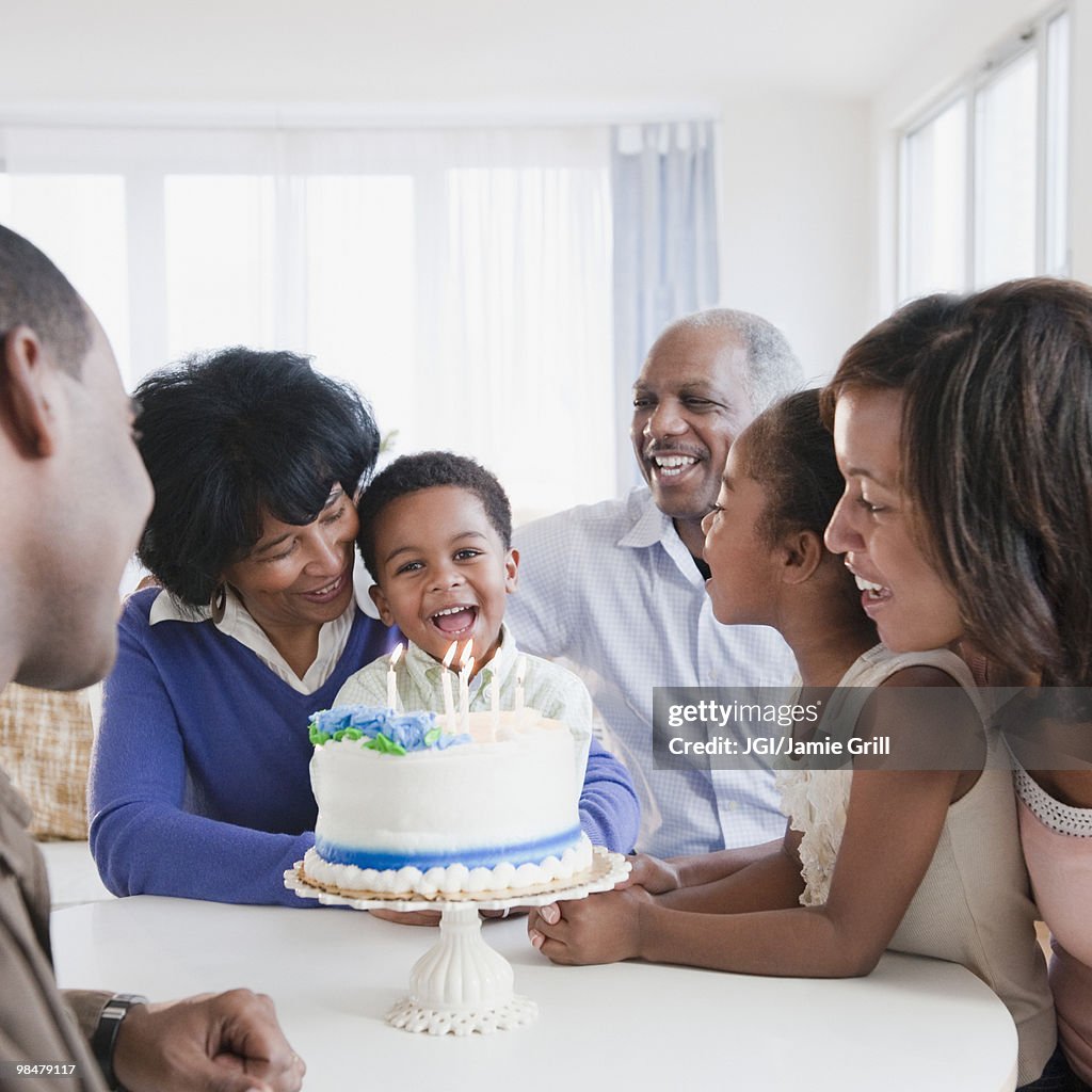 African American family watching grandson blow out birthday candles