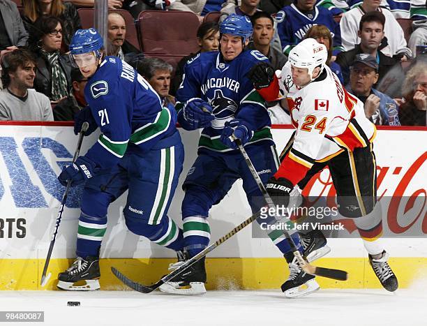 Craig Conroy of the Calgary Flames and Mason Raymond and Kyle Wellwood of the Vancouver Canucks battle for the puck during their game at General...
