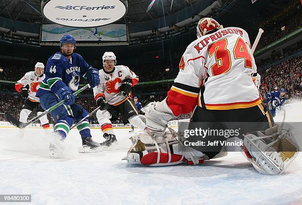 Nolan Baumgartner of the Vancouver Canucks and Jarome Iginla of the Calgary Flames look on as Miikka Kiprusoff of the Calgary Flames makes a save...