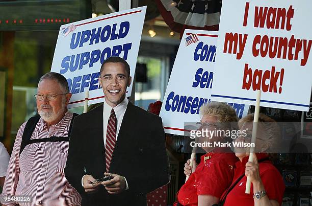 New Hampshire residents, Roger Rist, Robin Rist and Judy Berman holds signs while posing for a picture in front of a cardboard cut out of President...