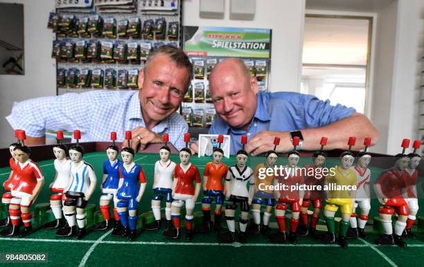 June 2018, Germany, Villingen-Schwenningen: The managers Matthias and Jochen Mieg kneeling in front of the Tipp-Kick figurines in the 32 current...