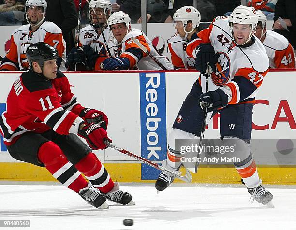 Andrew MacDonald of the New York Islanders plays the puck away from Dean McAmmond of the New Jersey Devils during the game at the Prudential Center...