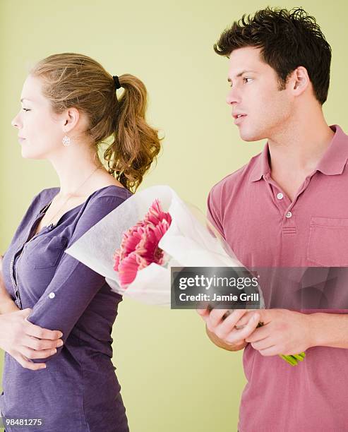 man offering unhappy girlfriend flowers - man giving flowers foto e immagini stock