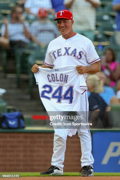 Texas Rangers Manager Jeff Bannister holds a jersey to be given to Pitcher Bartolo Colon for becoming the all-time winning Dominican pitcher prior to...