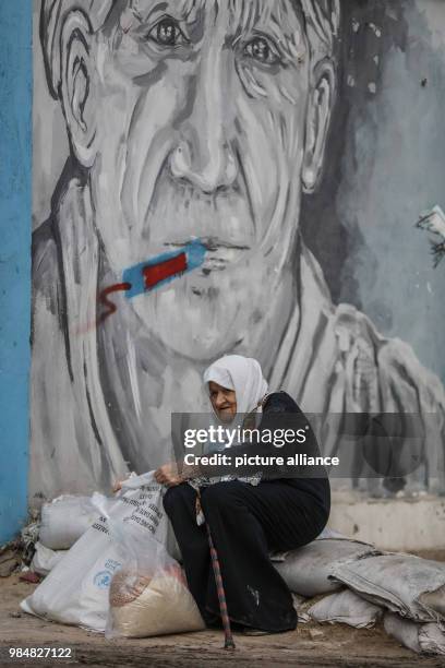 Palestinian woman sits next to a bag of food donations provided by the United Nations Relief and Works Agency for Palestine Refugees in the Near East...