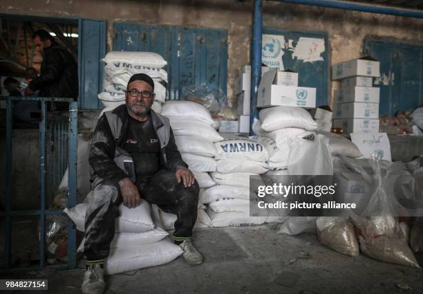 Palestinian man sits on sacks of flour provided by the United Nations Relief and Works Agency for Palestine Refugees in the Near East at a...