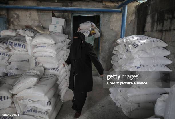 Palestinian man carries sacks of flour provided by the United Nations Relief and Works Agency for Palestine Refugees in the Near East at a...