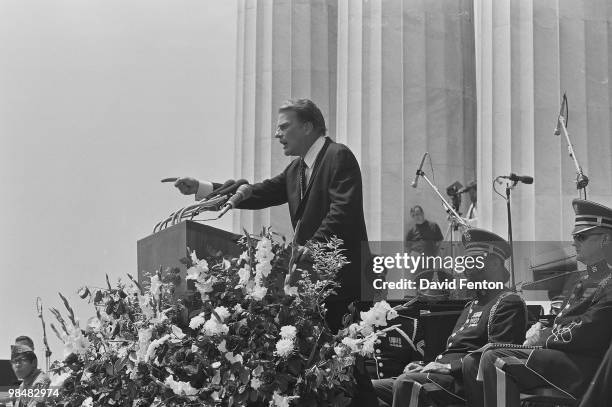 American evangelist Billy Graham points towards the crowd as he speaks to attendees from a podium on the steps of the Lincoln Memorial while...