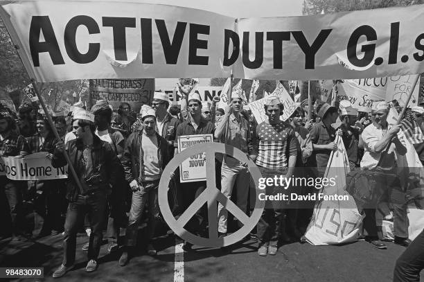 Group of active duty American soldiers out of uniform from the group 'GIs for Peace' carry a large banner and march amid others during a protest...