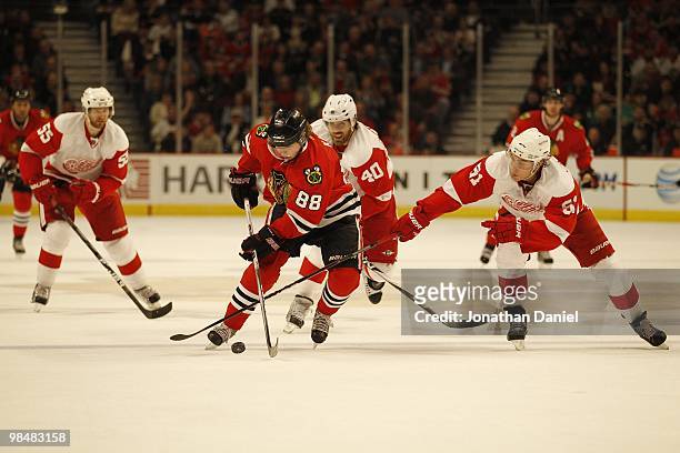 Patrick Kane of the Chicago Blackhawks skates past Valtteri Filppula and Henrik Zetterberg of the Detroit Red Wings at the United Center on April 11,...