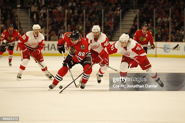 Patrick Kane of the Chicago Blackhawks skates past Valtteri Filppula and Henrik Zetterberg of the Detroit Red Wings at the United Center on April 11,...