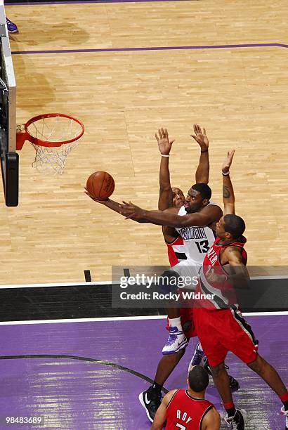 Tyreke Evans of the Sacramento Kings drives to the basket for a layup between Dante Cunningham and Marcus Camby of the Portland Trail Blazers during...