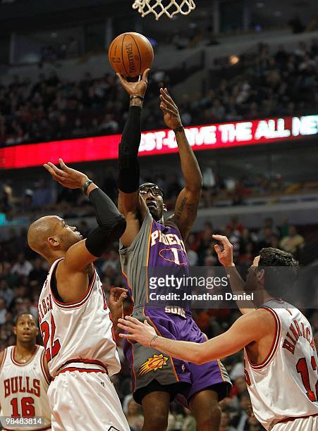 Amar'e Stoudemire of the Phoenix Suns puts up a shot over Taj Gibson and Kirk Hinrich of the Chicago Bulls at the United Center on March 30, 2010 in...