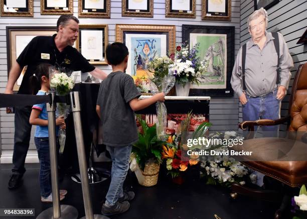 Gold & Silver Pawn Shop salesman Richard Tucker assists another employee's children, Maya Lee and Dylan Lee, place flowers at a memorial for Richard...