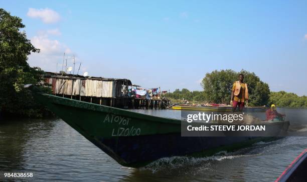 Pirogue speeds towards a fishermen's village outside Libreville called "grande poubelle" on June 21, 2018. - Foreign fishermen from - Nigerians and...