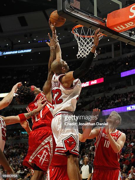 Taj Gibson of the Chicago Bulls reaches for a rebound between Jordan Hill and Chase Budinger of the Houston Rockets at the United Center on March 22,...