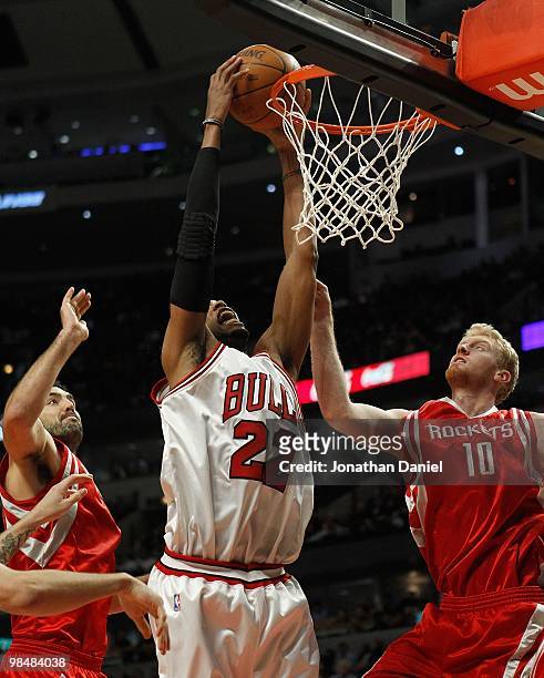 Taj Gibson of the Chicago Bulls goes up to dunk the ball between Luis Scola and Chase Budinger of the Houston Rockets at the United Center on March...