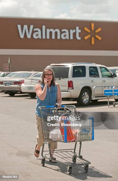 Rachel Zoellner pushes a shopping cart out of the Wal-Mart Store No. 1 in Rogers, Arkansas, U.S., on Thursday, April 15, 2010. Wal-Mart Stores Inc.,...