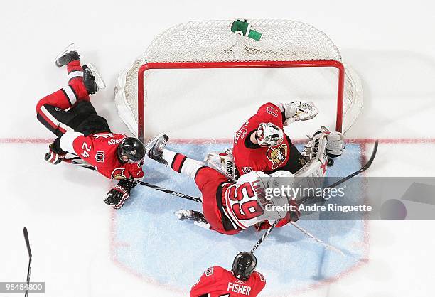 Anton Volchenkov, Brian Elliott and Mike Fisher of the Ottawa Senators defend against Chad LaRose of the Carolina Hurricanes as he dives across the...