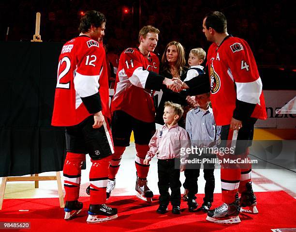 Captain Daniel Alfredsson of the Ottawa Senators shakes hands with teammate Chris Phillips prior to Alfredsson's 1000th game in their NHL game...