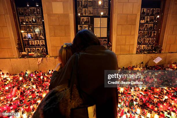 Woman embraces her daughter as they look at candles left by mourners and photographs of some of the 96 people killed when the Polish presidential...