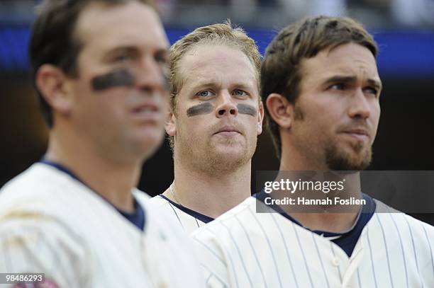 Left to right, Nick Punto, Justin Morneau and J.J. Hardy of the Minnesota Twins during the singing of God Bless America in the middle of the seventh...